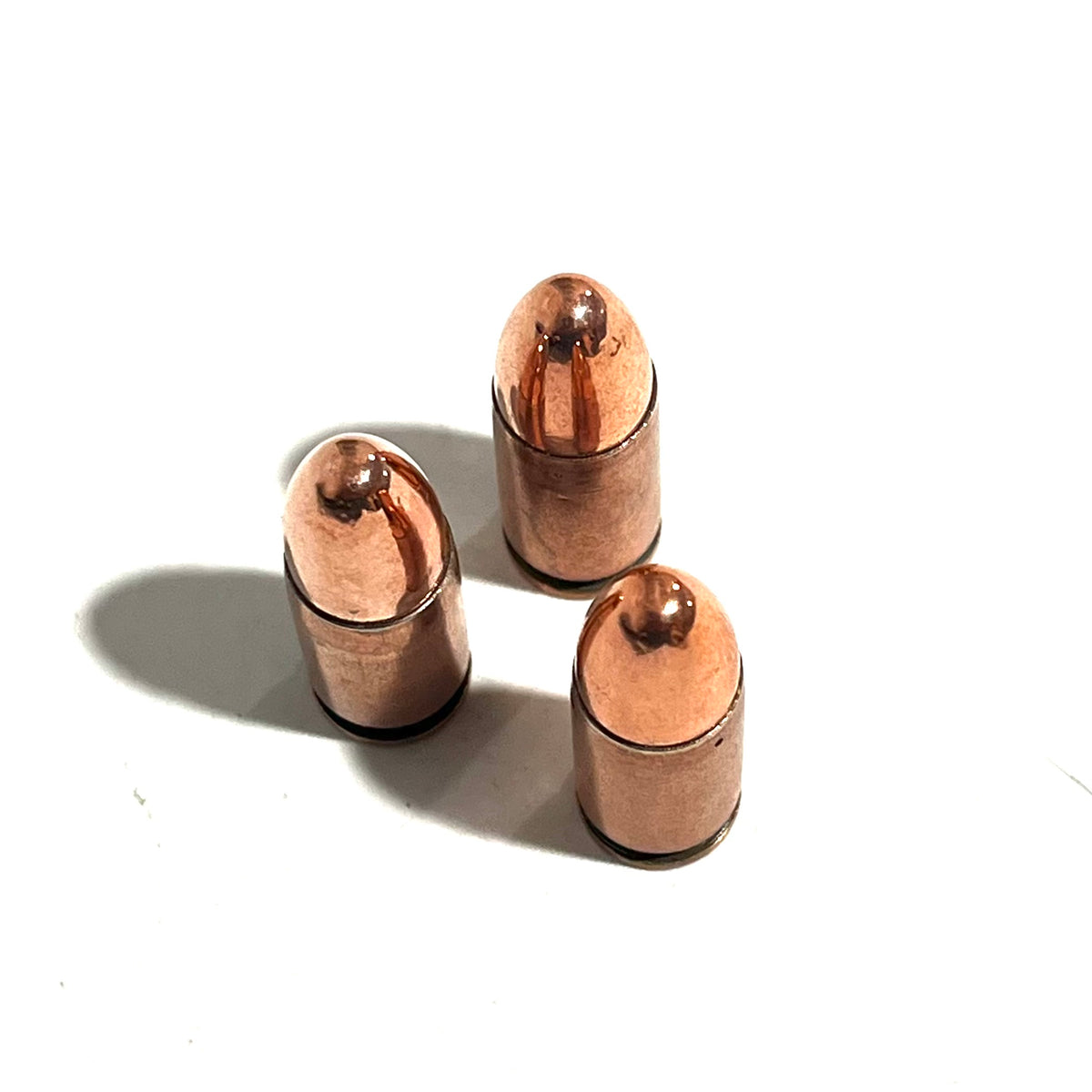 3 copper 9mm Luger dummy rounds viewed from above showing round nose bullet tips