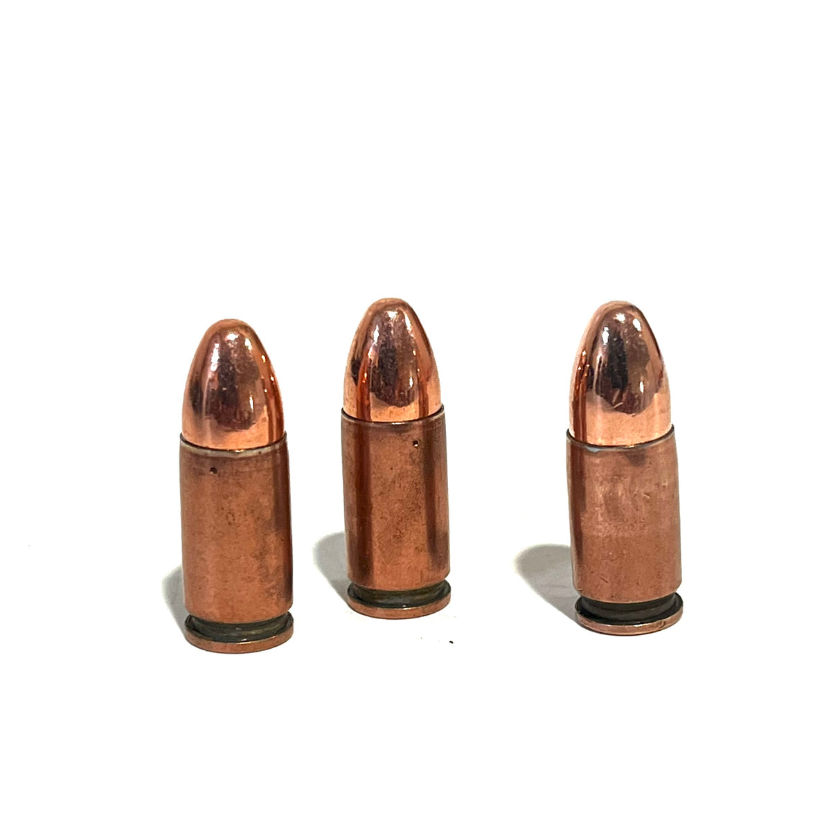 3 copper 9mm Luger dummy rounds standing upright on a white background