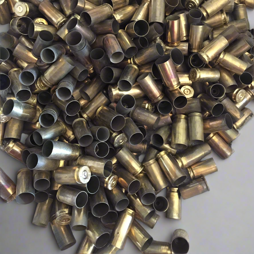 Dense bulk pile of uncleaned 9mm spent brass casings showing open mouths and primer bases.