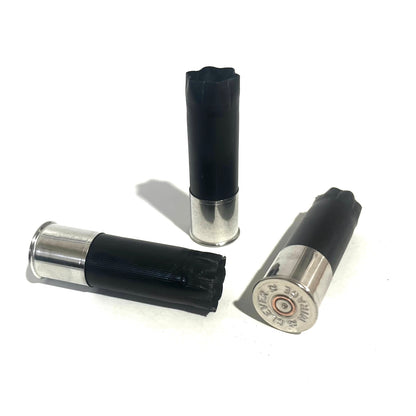 Two black shotgun shells with high brass bottoms lying down and one showing a Clever Mirage 12 headstamp