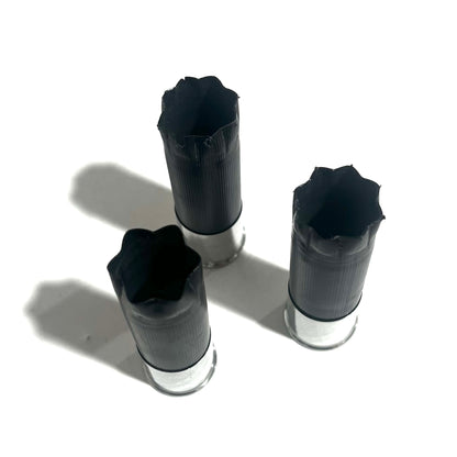 Three black shotgun shells with high brass bottoms viewed from above showing fluted crimped tops