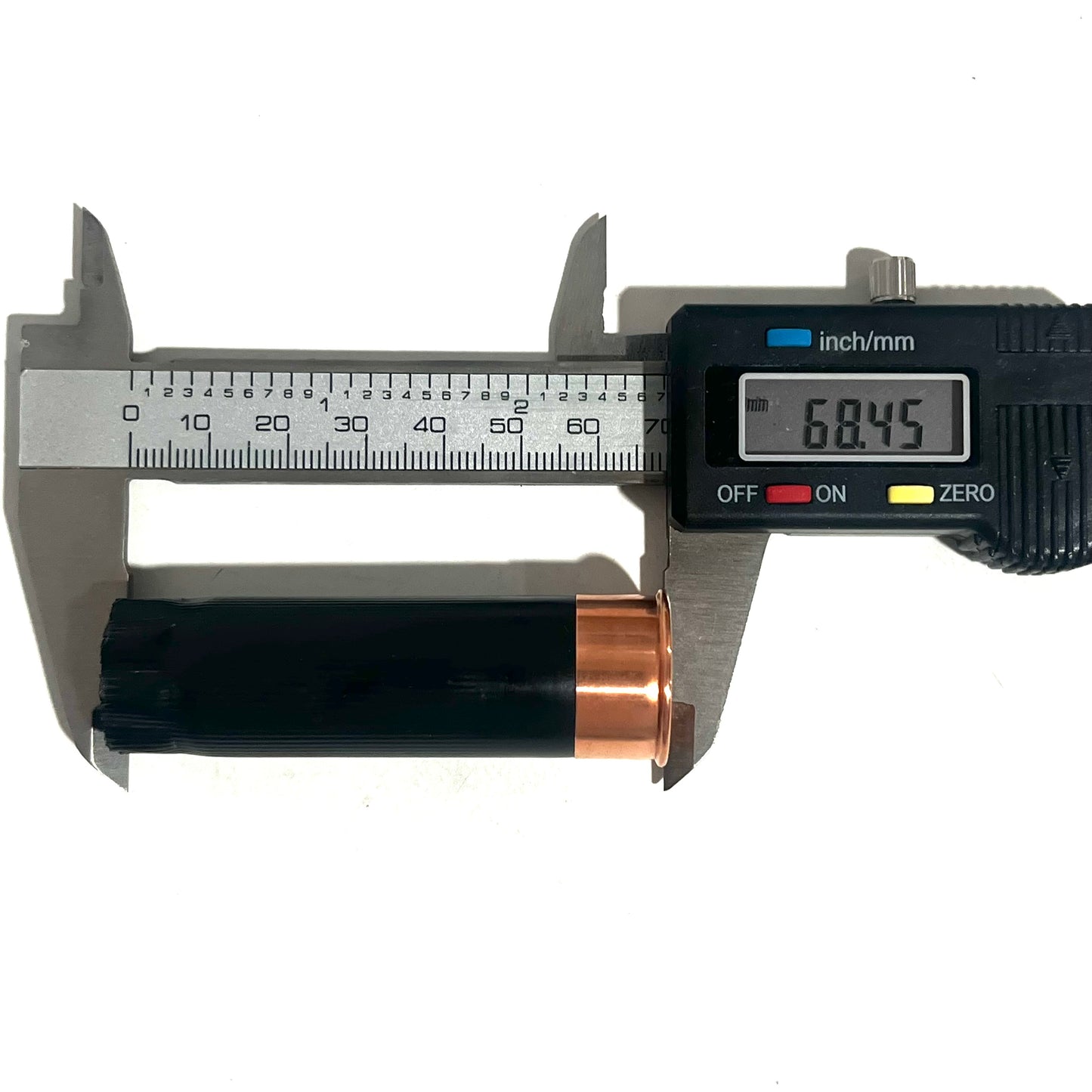 Digital caliper measuring the length of a black shotgun shell hull with copper base at 68.45mm