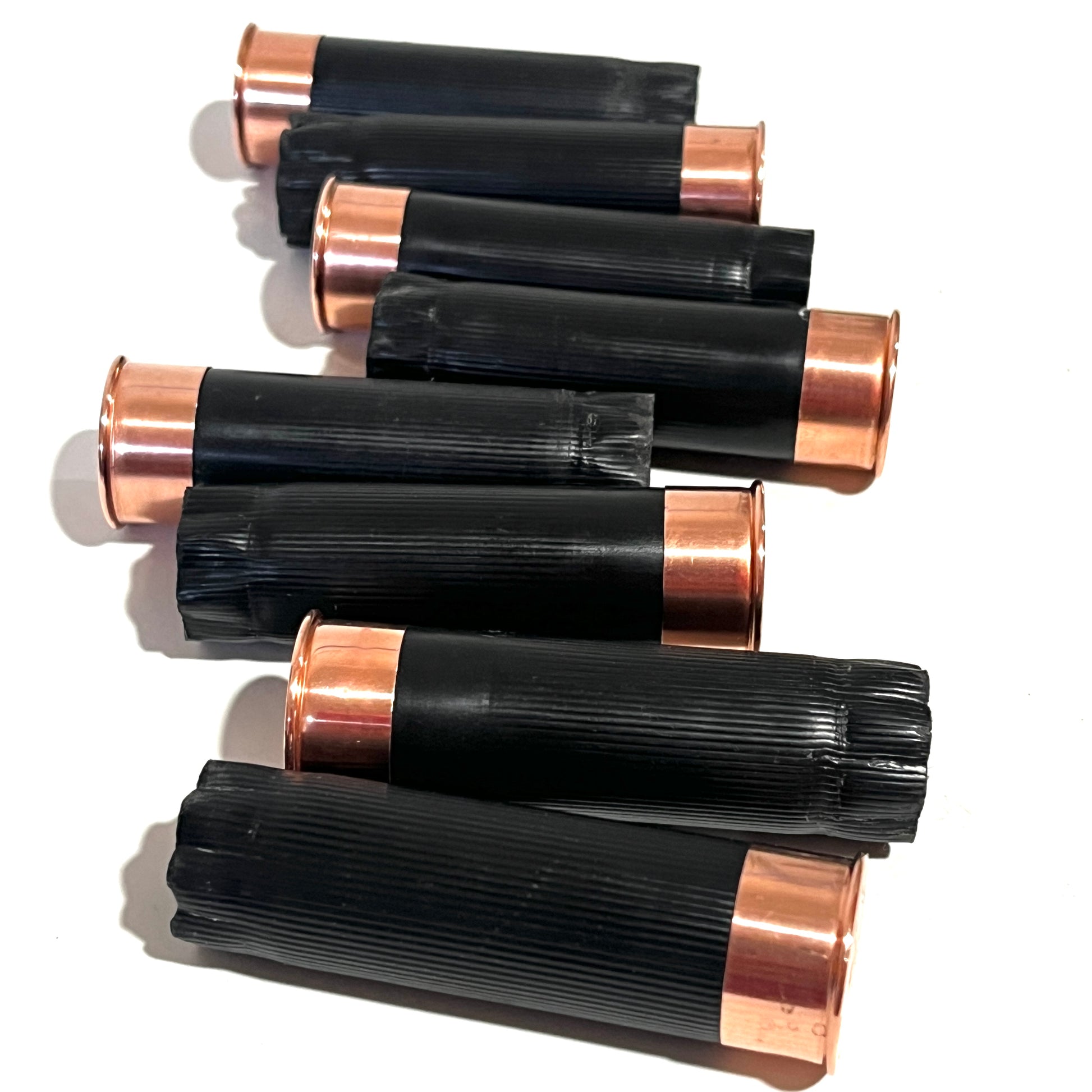 8 black shotgun shell hulls with copper bases stacked in a cluster on white background