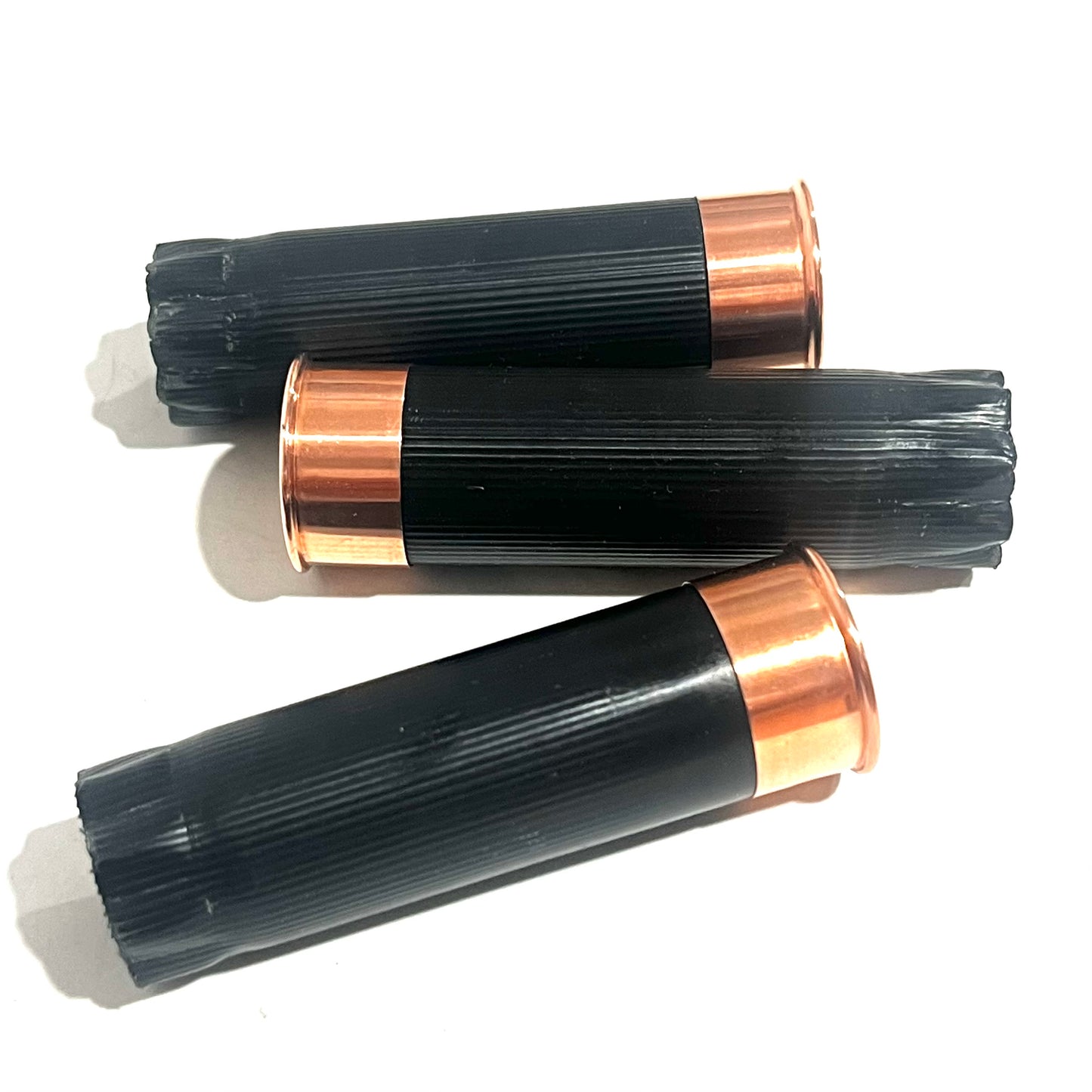 3 black shotgun shell hulls with copper bases standing upright on white background