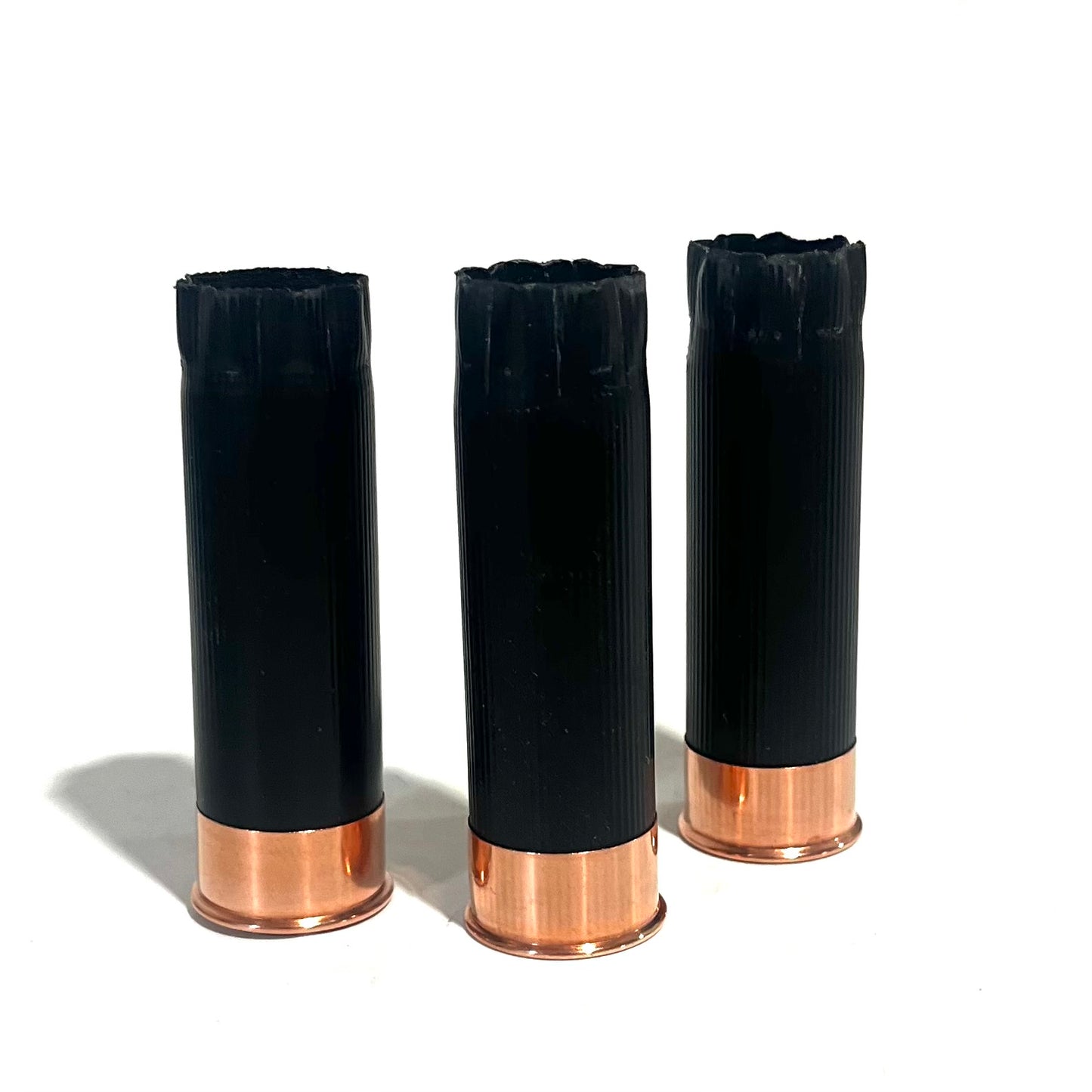 3 black shotgun shell hulls with copper bases viewed from open crimped end, star-shaped crimp pattern