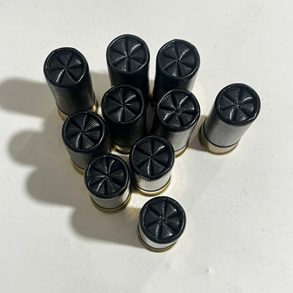 Top view of black inert, dummy rounds showing six star crimp on a white background