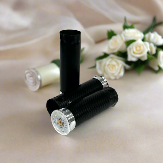 Black shotgun shells with silver bases beside white roses and sheer fabric, one cream shell also visible