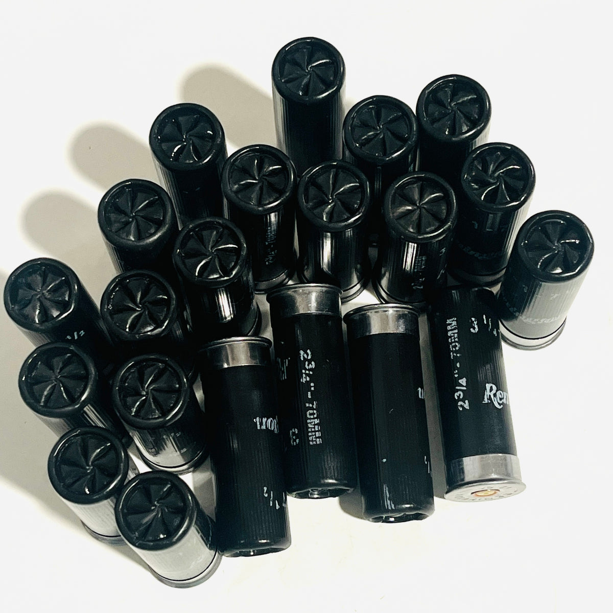 Group of black once-fired 12 gauge dummy rounds standing and lying together, star crimps facing up