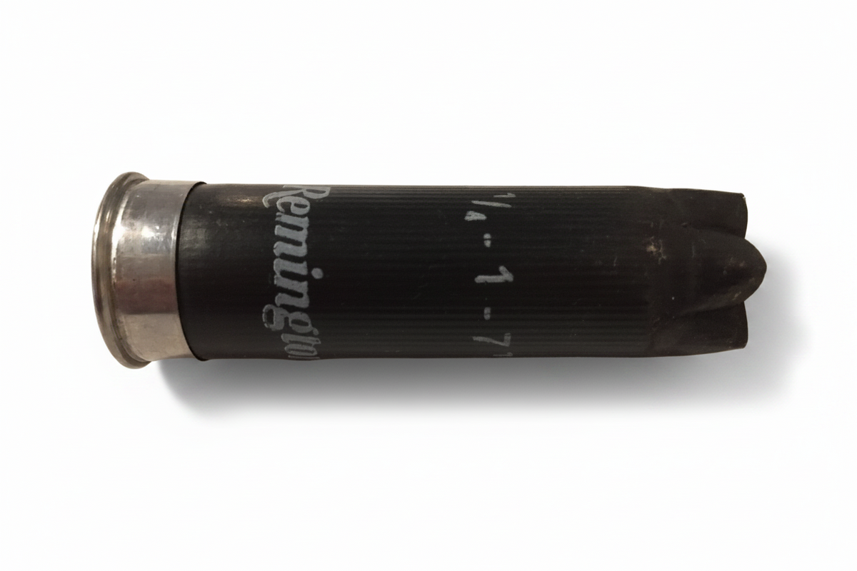 Single black spent Remington 12 gauge empty shotgun hull with silver base lying horizontally showing white printed lettering.