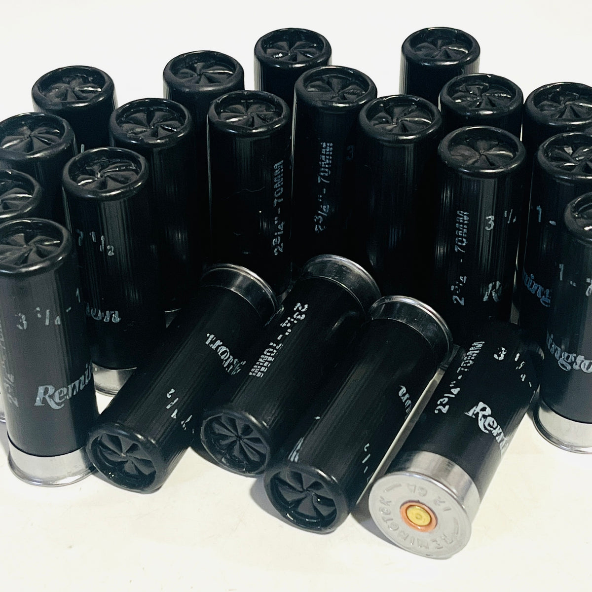 Black spent Remington 12 gauge shotgun shells standing in rows, four lying in front with crimps facing out