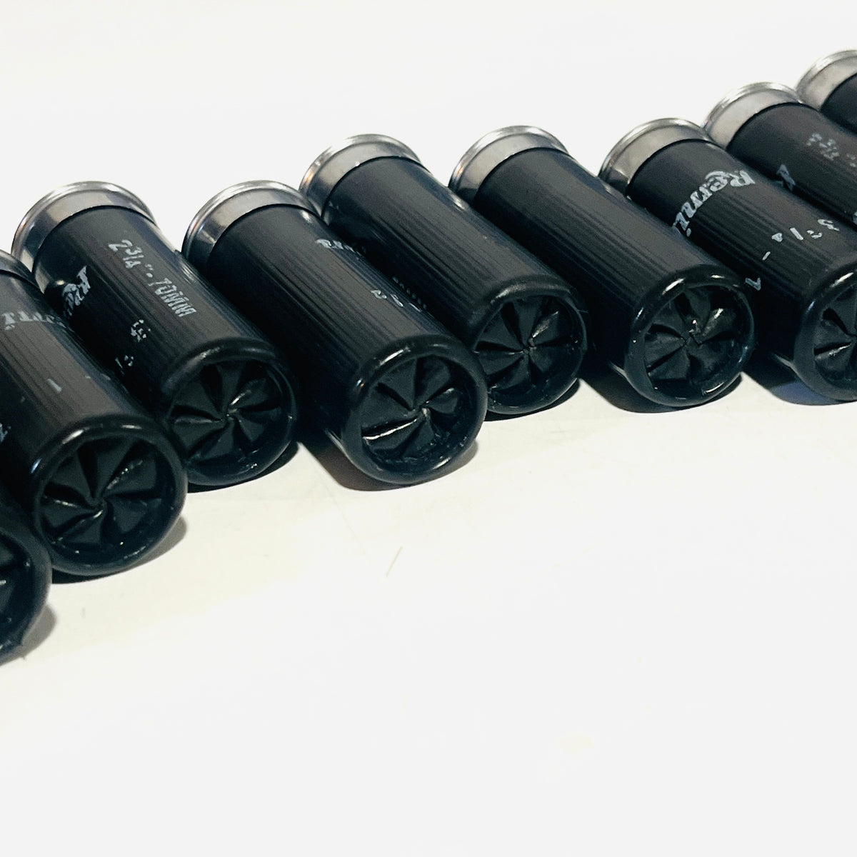 Row of used black dummy shells lying on their sides, sealed star-crimp ends facing the camera