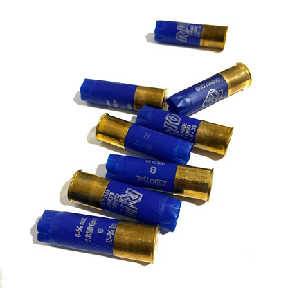 8 empty blue 12 gauge RIO shotgun shells with brass bases scattered on a white background