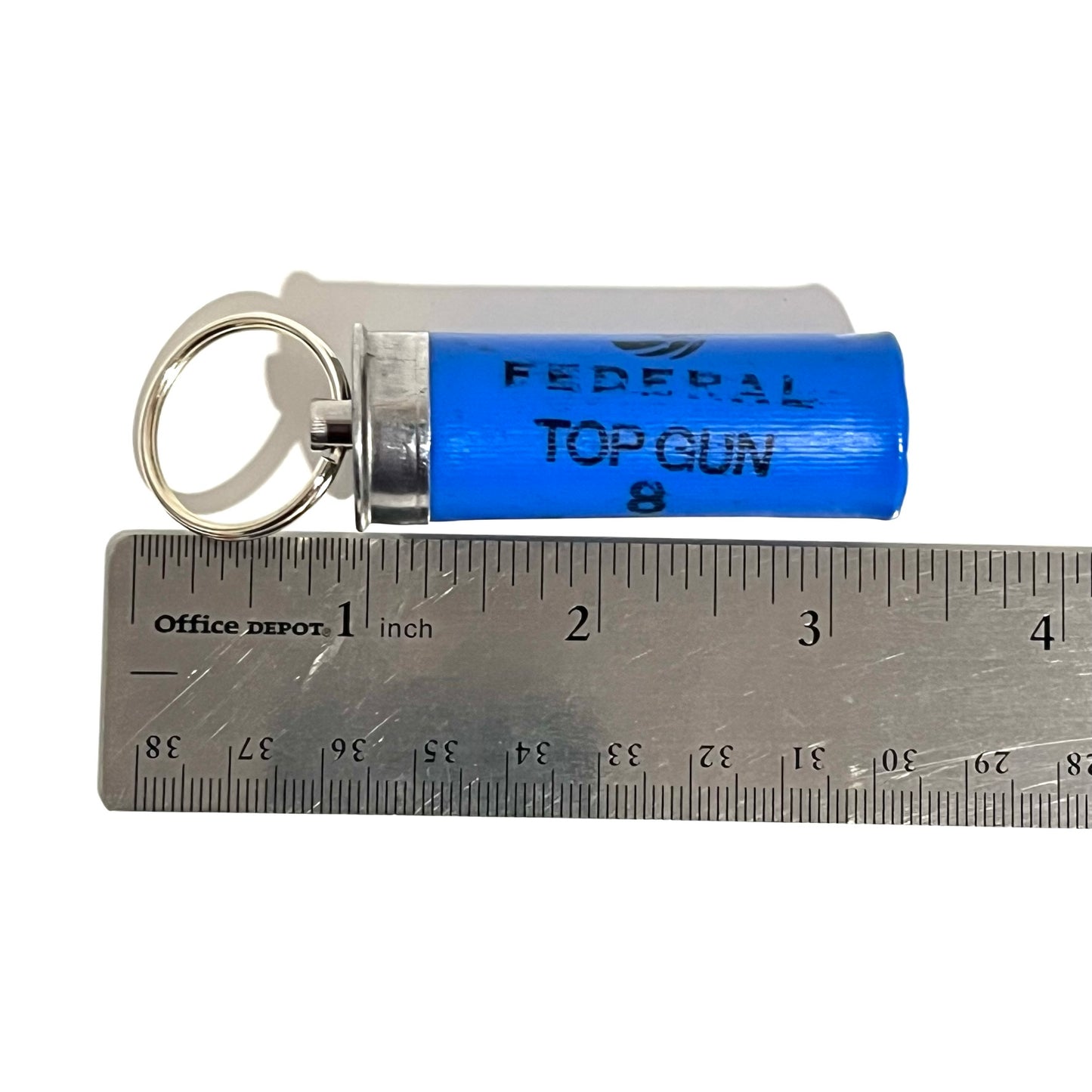 Blue 12 gauge shotgun shell keychain resting above a metal ruler demonstrating total length measurement.