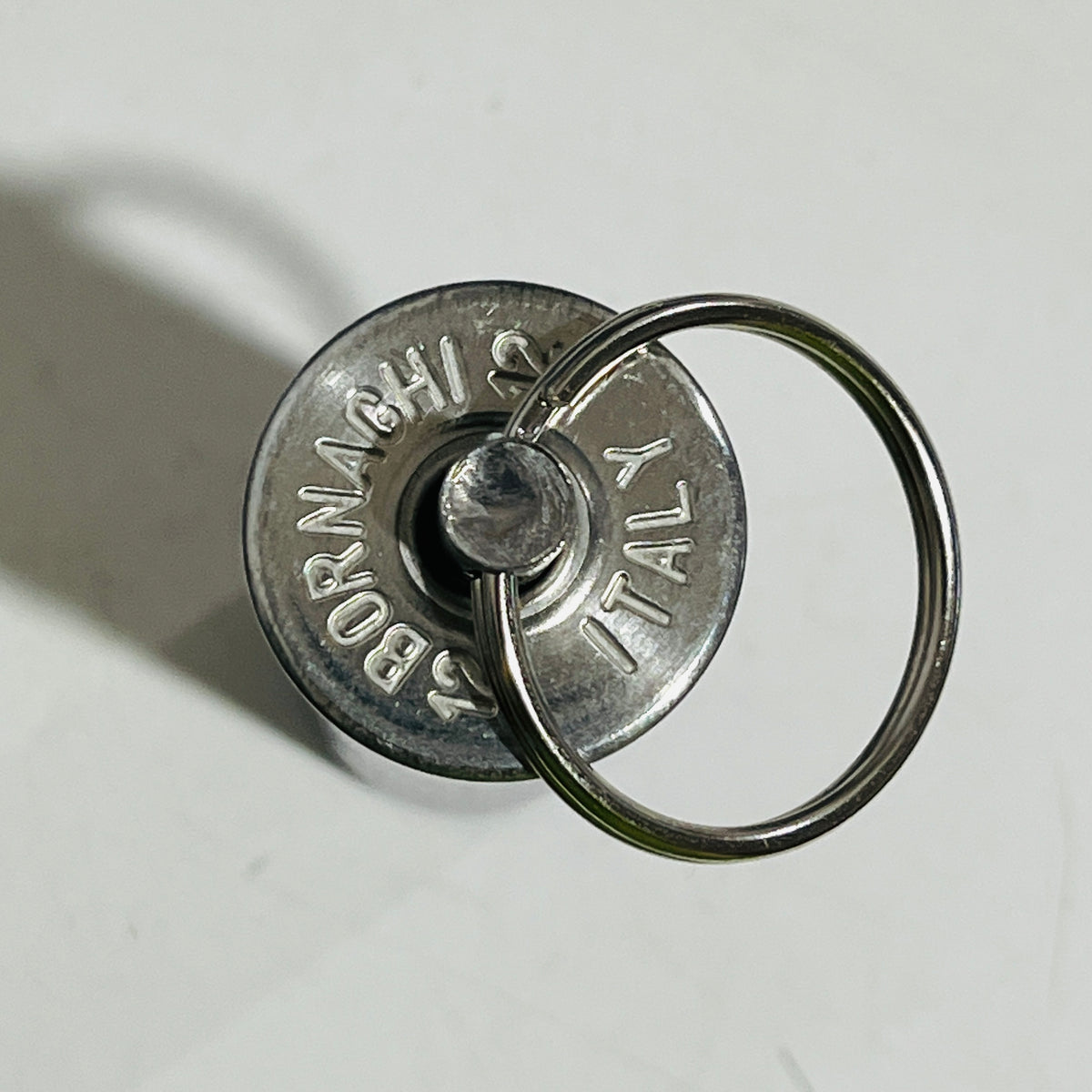 Base of a spent shell keychain stamped BORNAGHI 12 ITALY, with the swivel pin centered and a split ring attached