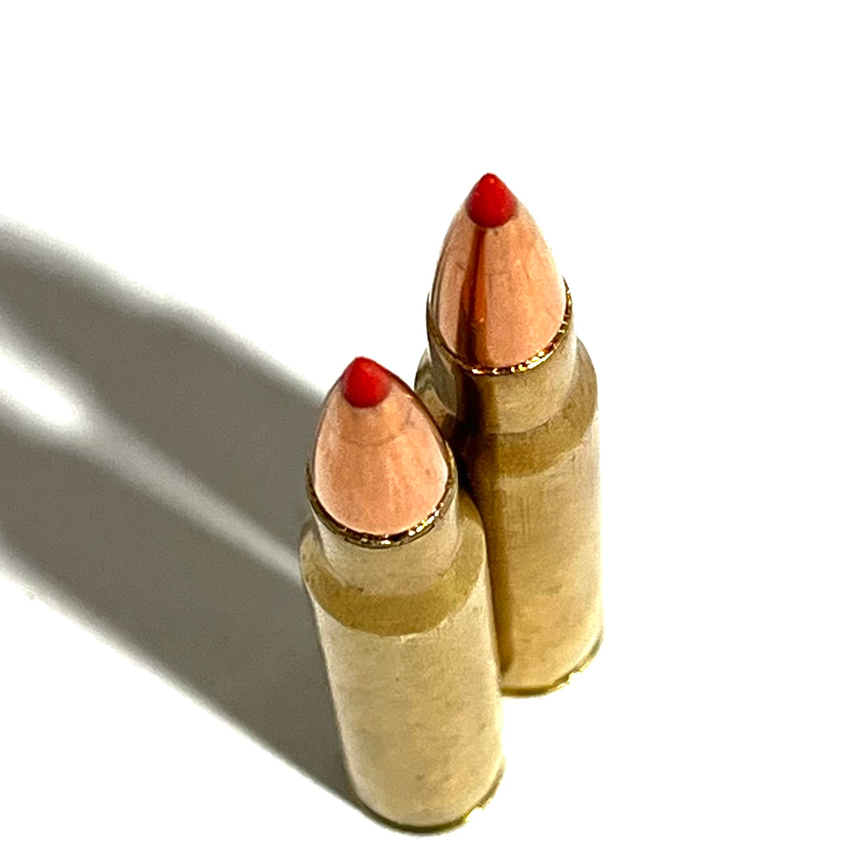 Two tarnished 30-06 brass shells with red tip bullets standing upright on white background.