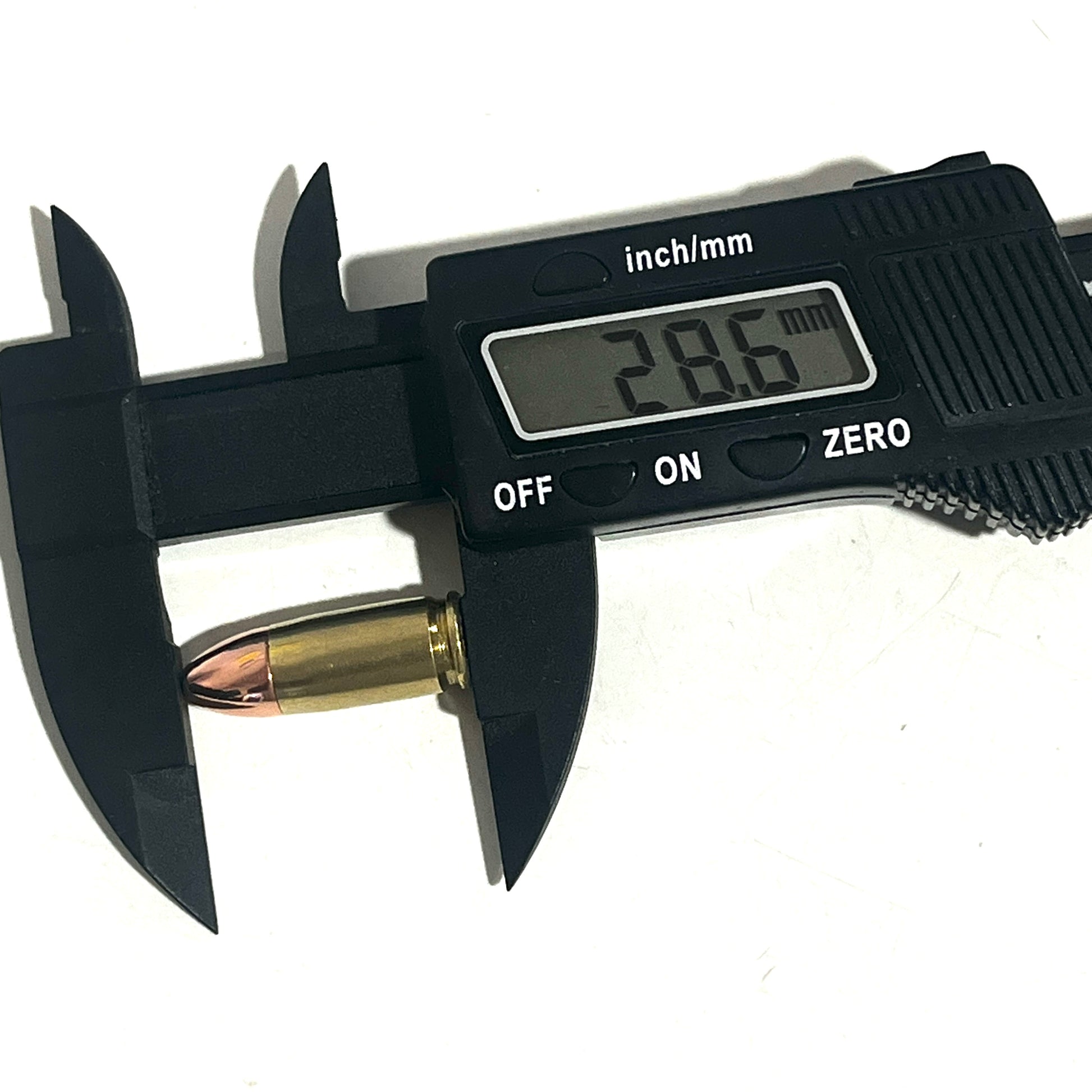 Black digital caliper measuring the total length of a brass 9mm dummy round, showing a display reading of 28.6 mm.