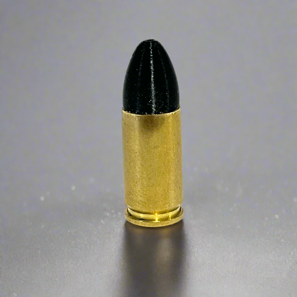 Single fake 9mm Luger dummy round with black painted tip standing on a gray gradient background