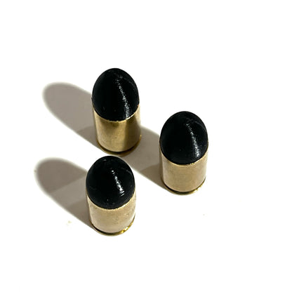3 fake 9mm Luger dummy rounds with black painted tips standing on white background