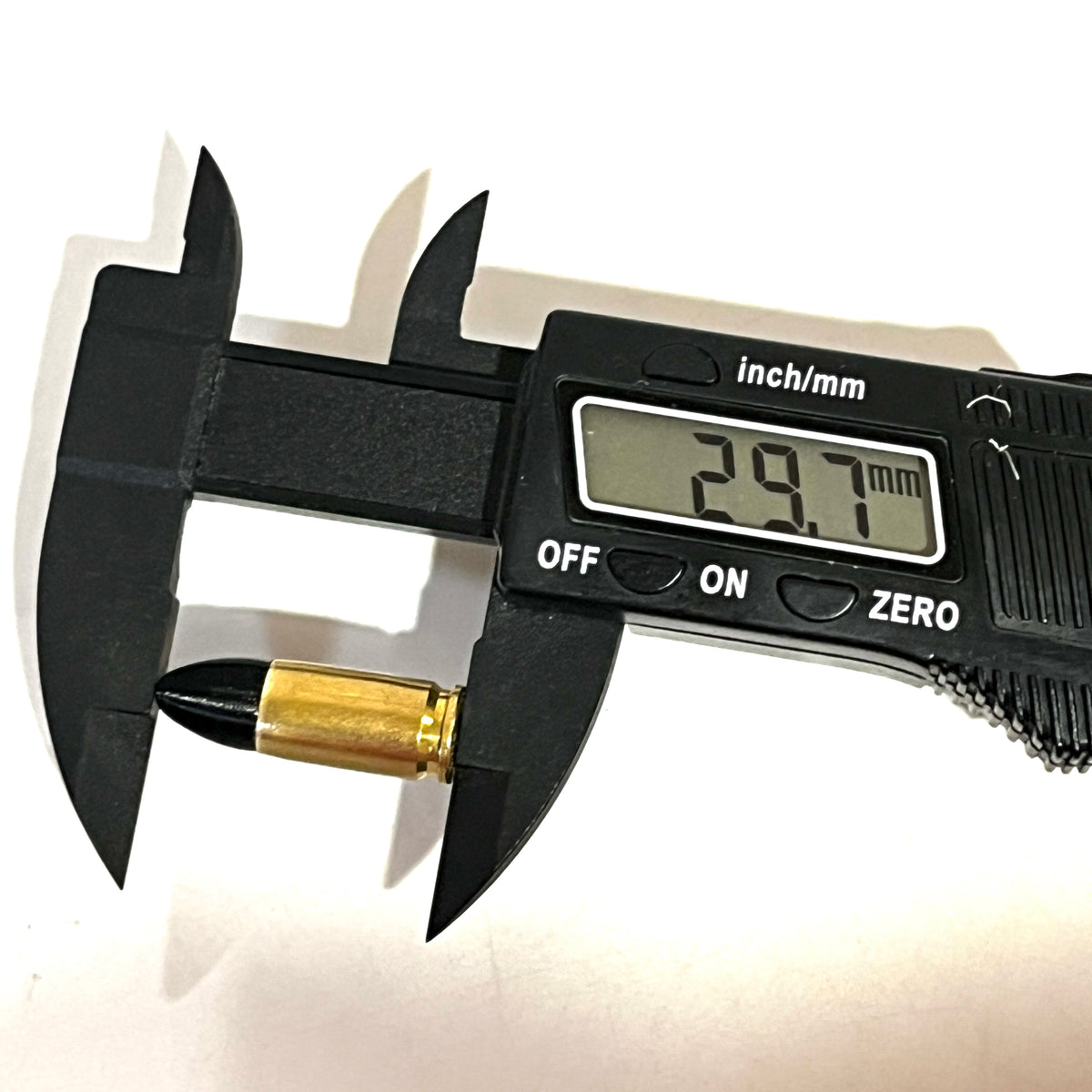 Digital caliper measuring the length of a fake 9mm Luger dummy round with black tip at 29.7mm