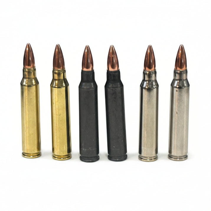 Six .223/5.56 cartridges in brass, black, and silver finishes stand in a row near a blue cloth backdrop.