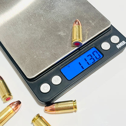 One once-fired brass cartridge on a digital scale reading 11.30 g, with more copper-tipped rounds nearby