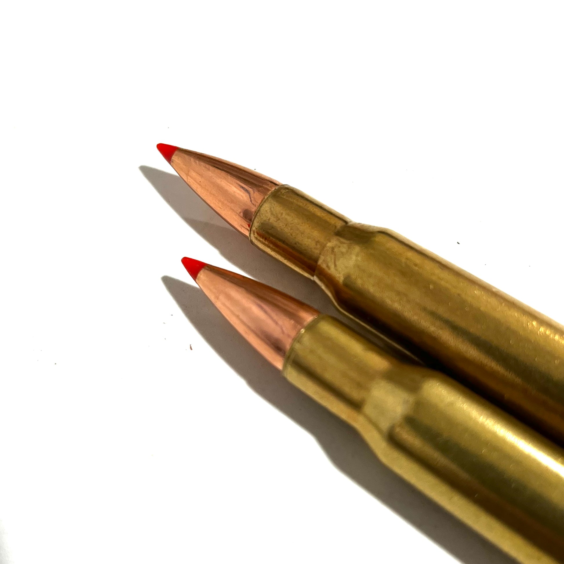 Two brass dummy rounds with red tips angled diagonally on white background.