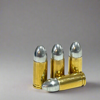 Four brass 9mm dummy shells, three standing upright and one crossed in front, on a gray background.