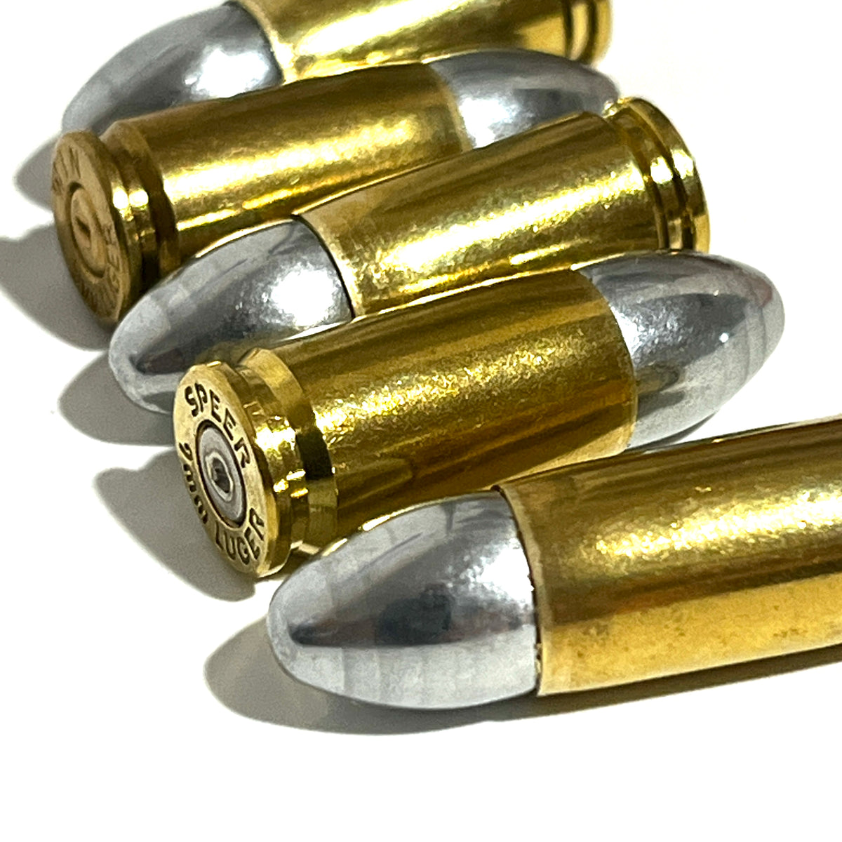 Several brass 9mm Luger hulls fanned out, with a Speer headstamp visible on one base.