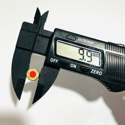 Base of a spent brass casing with red primer held in a digital caliper reading 9.9 mm diameter