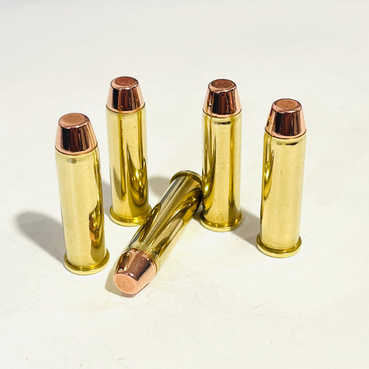 Five spent brass 357 Magnum dummy cartridges, four standing with copper flat-nose bullets up and one lying
