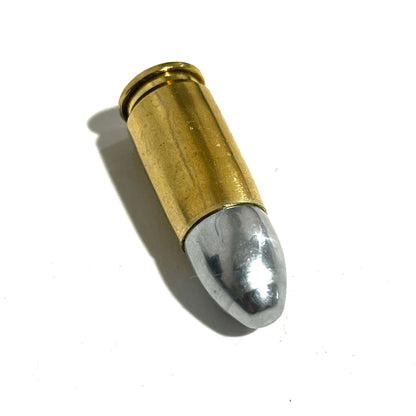 A single brass 9mm dummy casing lying diagonally on a white background.