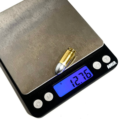 A brass 9mm cartridge rests on a digital scale reading 12.76 grams.