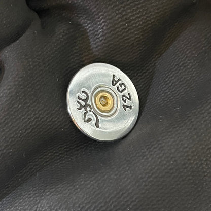 Silver Browning 12 gauge shotgun shell slice resting on a black-gloved hand
