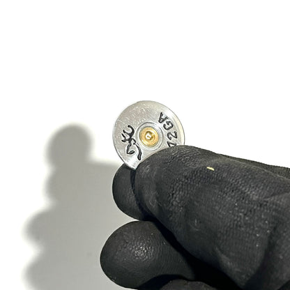 Small silver Browning shotgun shell slice held between black-gloved fingers