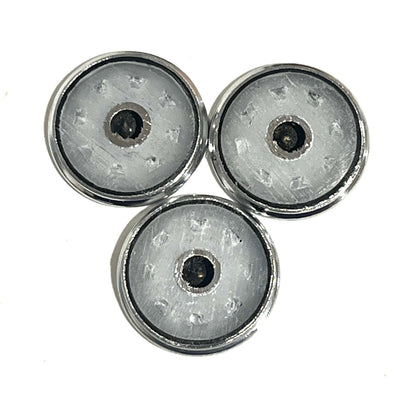 Reverse sides of three silver Browning shotgun shell slices with dark center openings