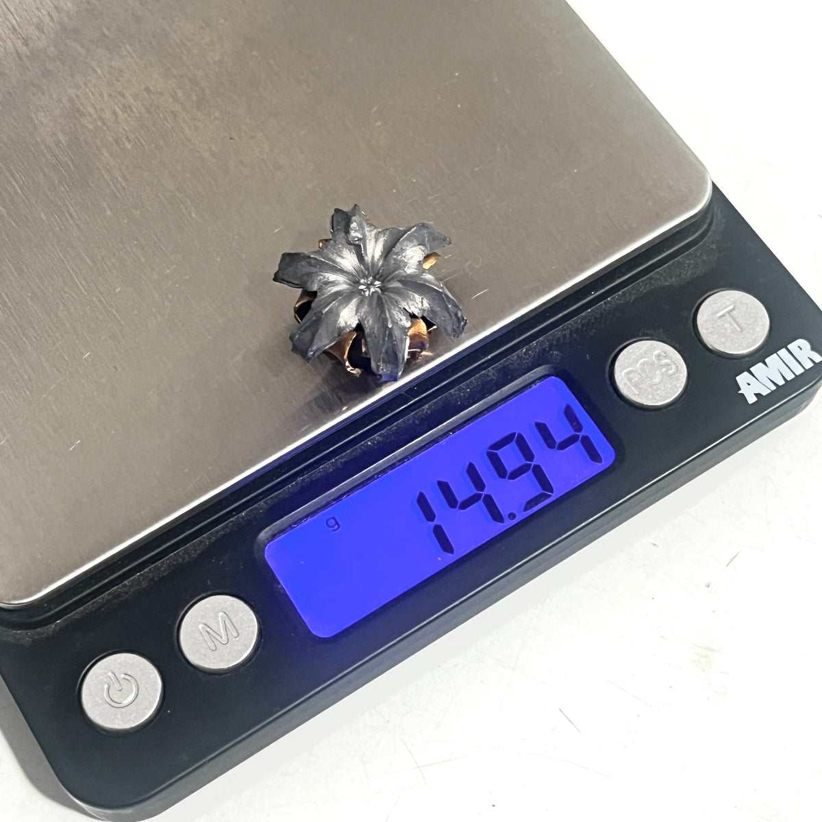 A .45 ACP bullet blossom hollow point  flower charm on a digital scale reading 14.94 grams