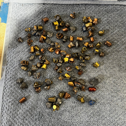 Pile of deformed spent bullet fragments on a gray carpet