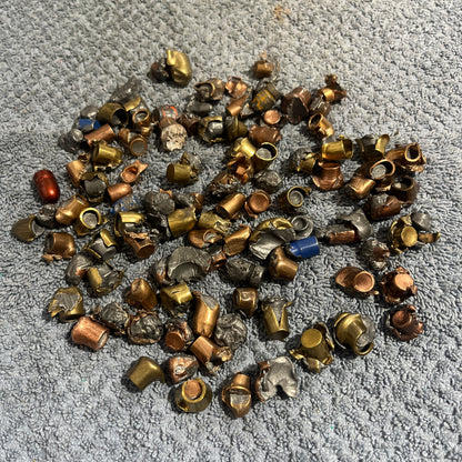 Pile of deformed spent bullet fragments on a gray towel next to a blue tarp