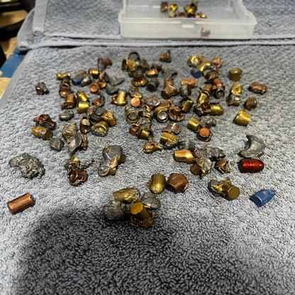 Pile of deformed spent bullet fragments on a gray towel
