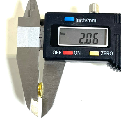 Digital calipers measuring the 2.06mm thickness of a thin-cut .223 brass bullet slice for jewelry making.