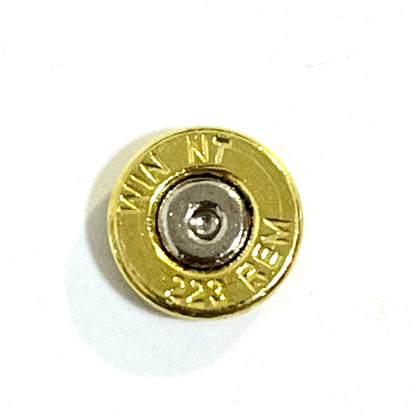 Close-up of a thin-cut polished brass 223 bullet slice measuring approximately 2mm thick.