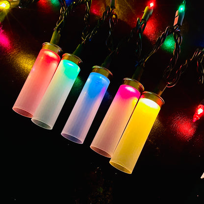 Five clear empty hulls fitted over Christmas mini lights, glowing red, green, blue, pink and yellow against a dark background