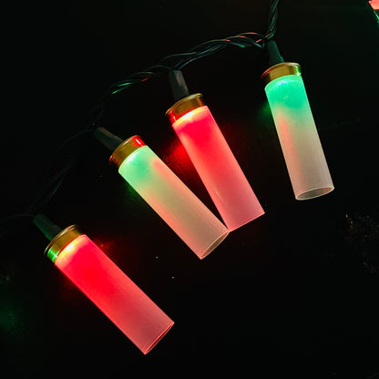 Four clear empty casings strung diagonally on a light strand, alternating red and green glow against a black background