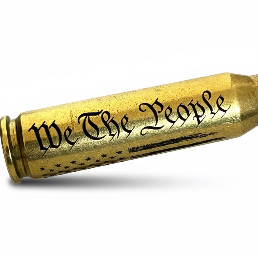Close-up of We The People and American flag engraving on a 308 win authentic once-fired brass dummy round casing.
