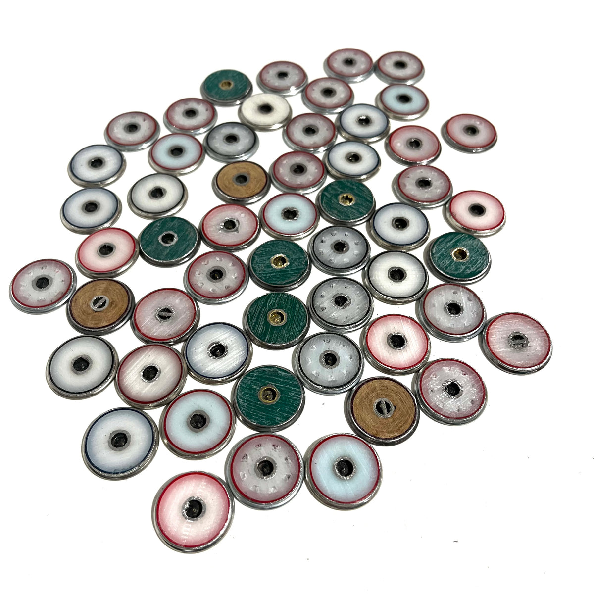 A pile of silver-rimmed shotgun shell slices showing colorful plastic wad centers in white, blue, green, and tan