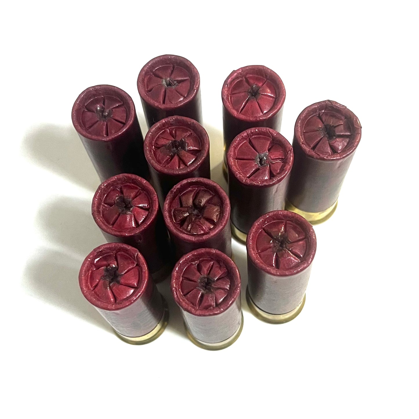 Overhead view of 10 dark red 12 gauge dummy shotgun shells with star crimped tops