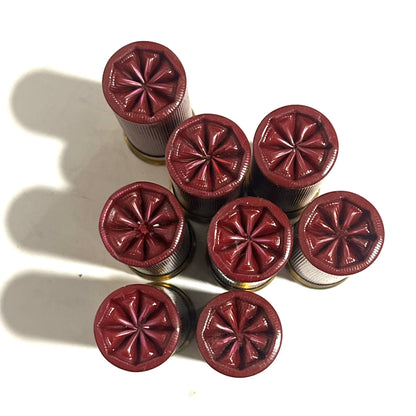 Overhead view of 8 dark red 12 gauge dummy shotgun shells with star crimped tops arranged in a cluster