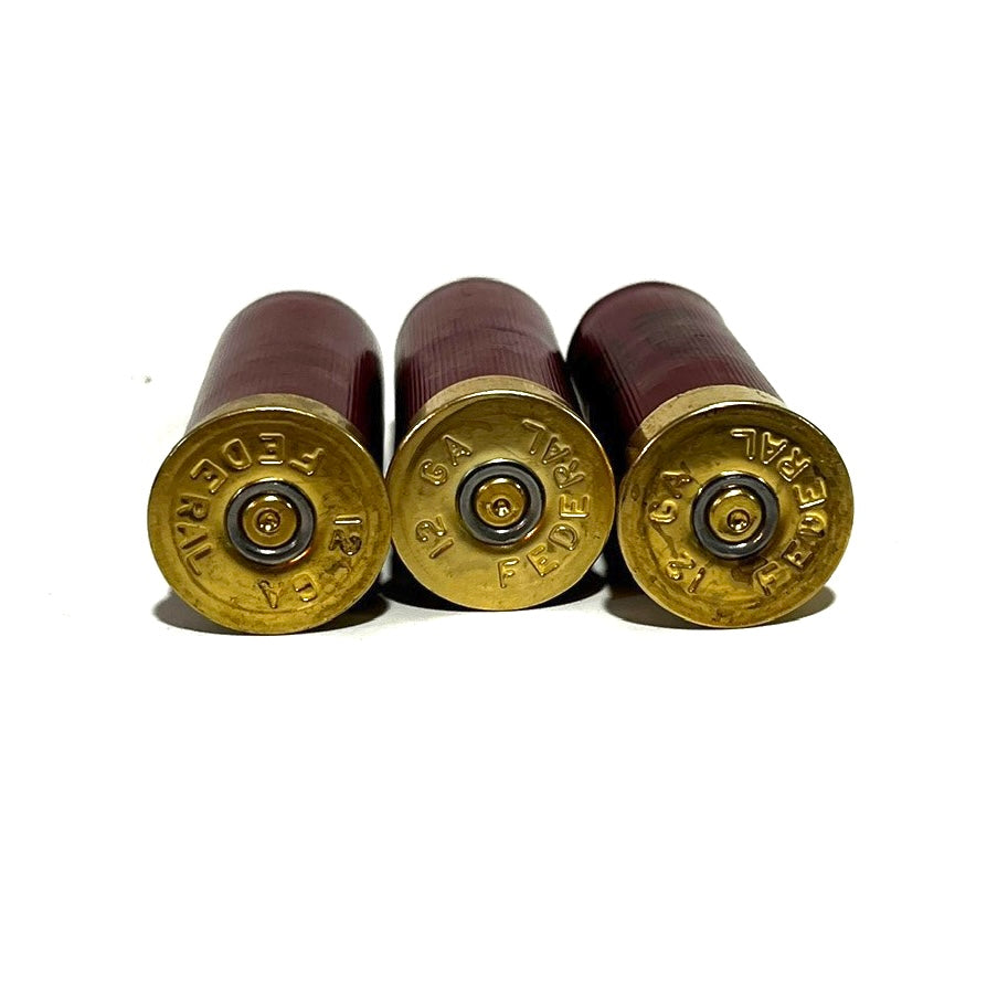 Three Federal 12 gauge dummy shotgun shells standing upright showing gold brass headstamps stamped Federal 12 GA