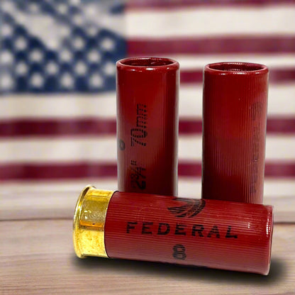 Two dark red Federal 12 gauge dummy training rounds with gold brass bottoms on a white background