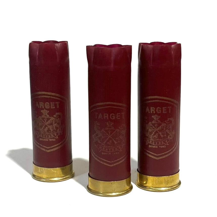 Three Dark Red Herter's 12 Gauge Shotgun Shells Standing